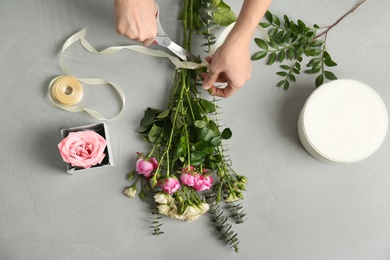 Photo of Female florist making beautiful bouquet at table, top view