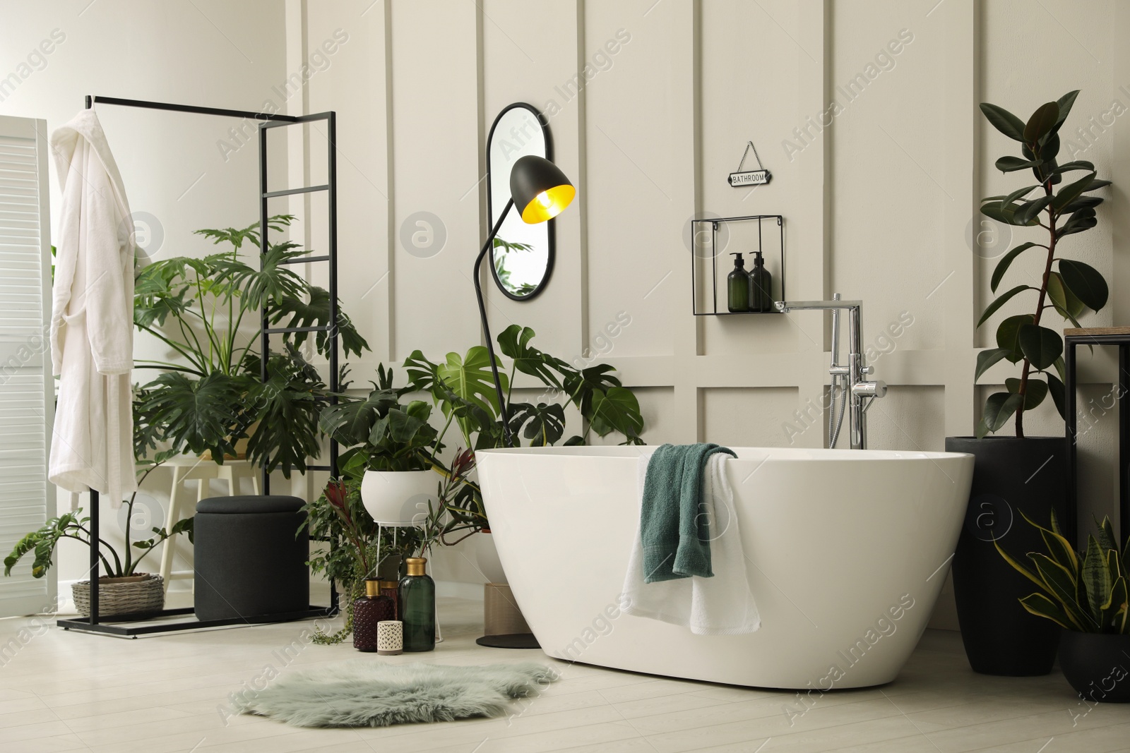 Photo of Stylish bathroom interior with modern tub and beautiful houseplants. Home design