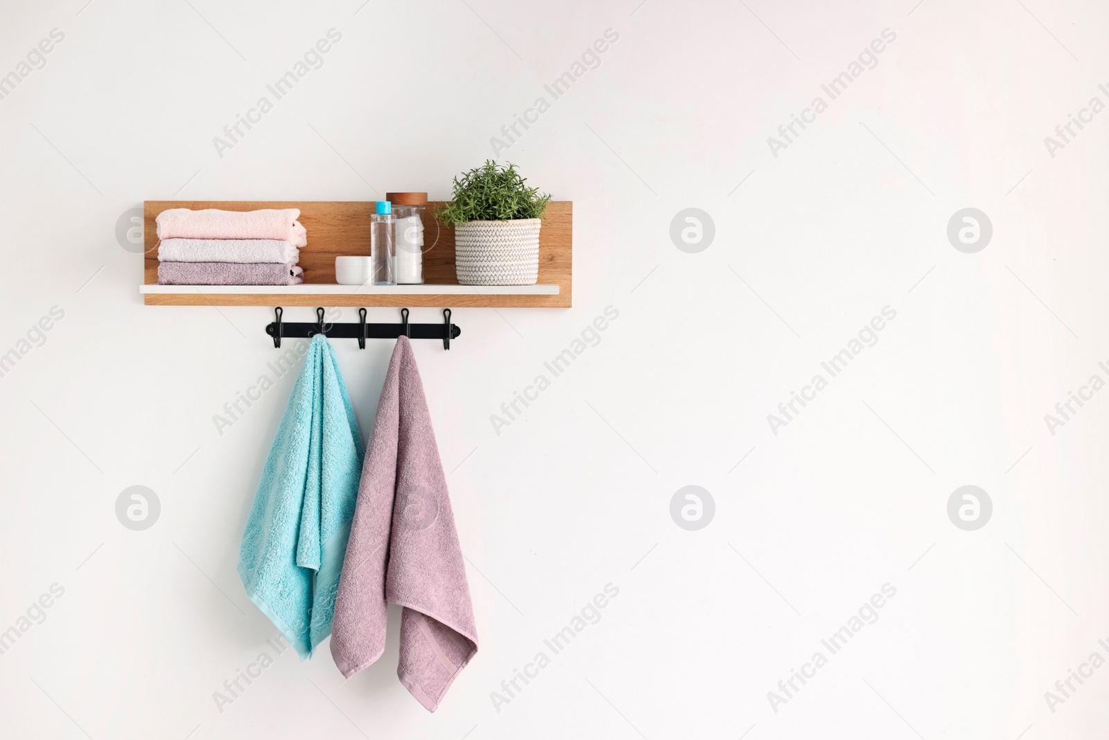 Photo of Clean towels, houseplant and toiletries on shelf indoors. Space for text