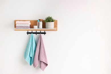 Photo of Clean towels, houseplant and toiletries on shelf indoors. Space for text