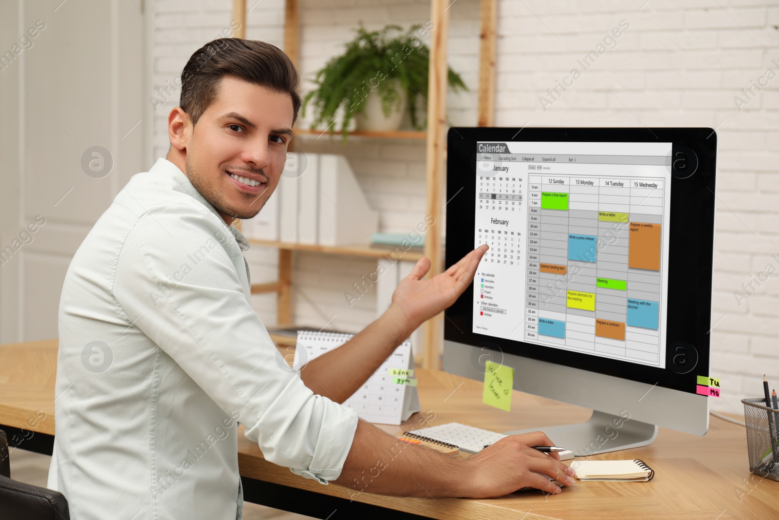 Photo of Handsome man using calendar app on computer in office