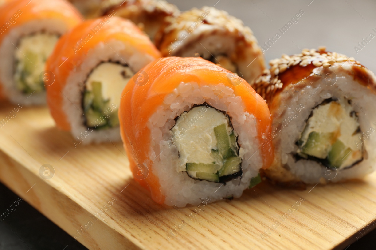Photo of Delicious sushi rolls on wooden tray, closeup