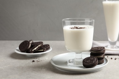 Glass with milk and chocolate cookies on table against grey background. Space for text