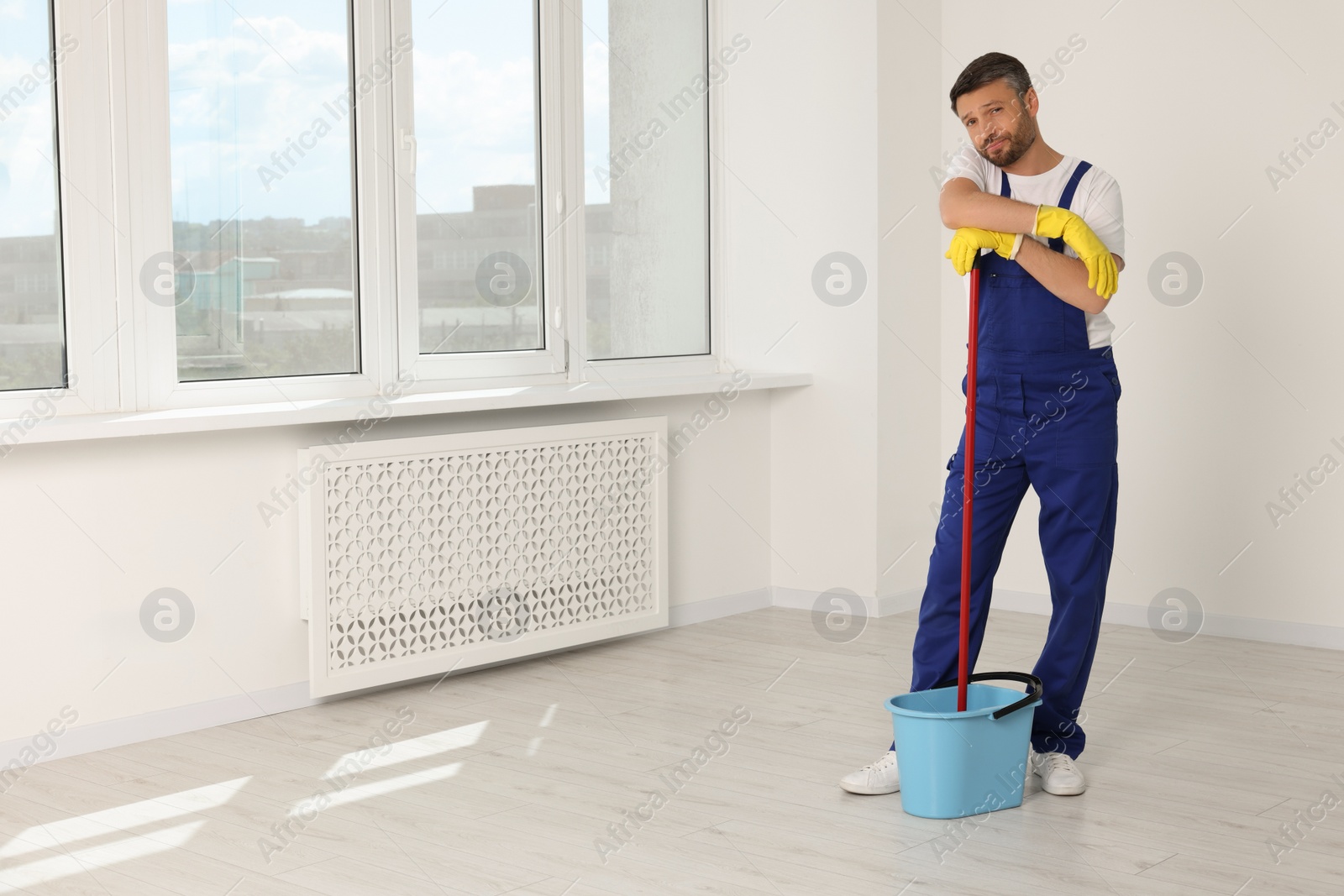 Photo of Man with mop in bucket indoors. Space for text