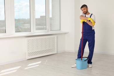 Photo of Man with mop in bucket indoors. Space for text