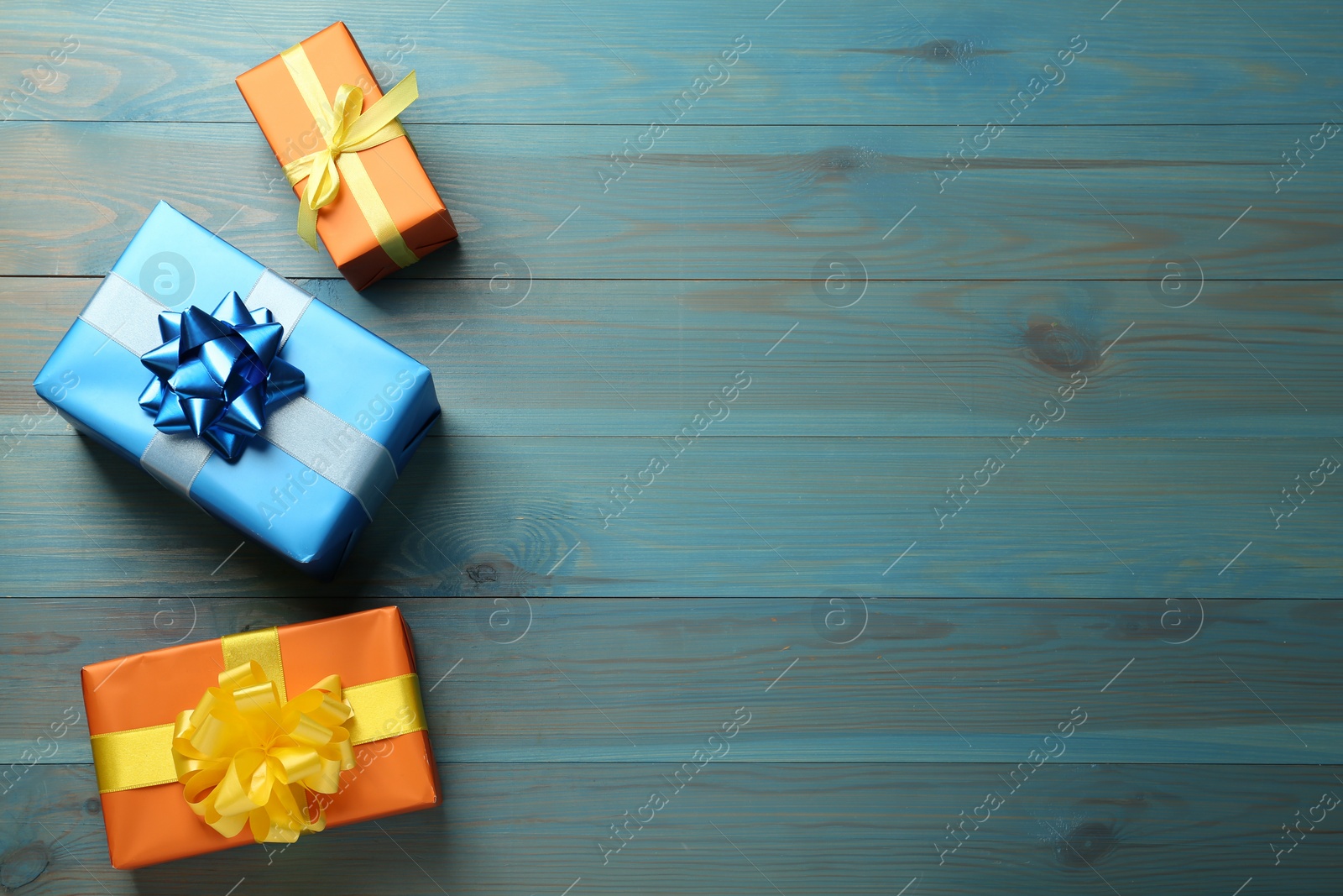 Photo of Different gift boxes on light blue wooden table, flat lay. Space for text