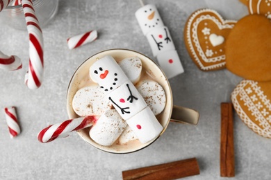 Flat lay composition with funny snowman made of marshmallows on grey table