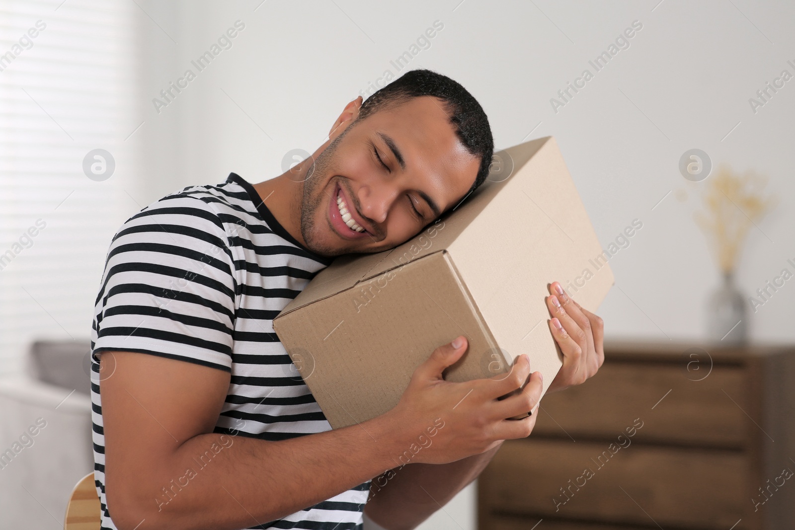 Photo of Happy young man with parcel at home. Internet shopping