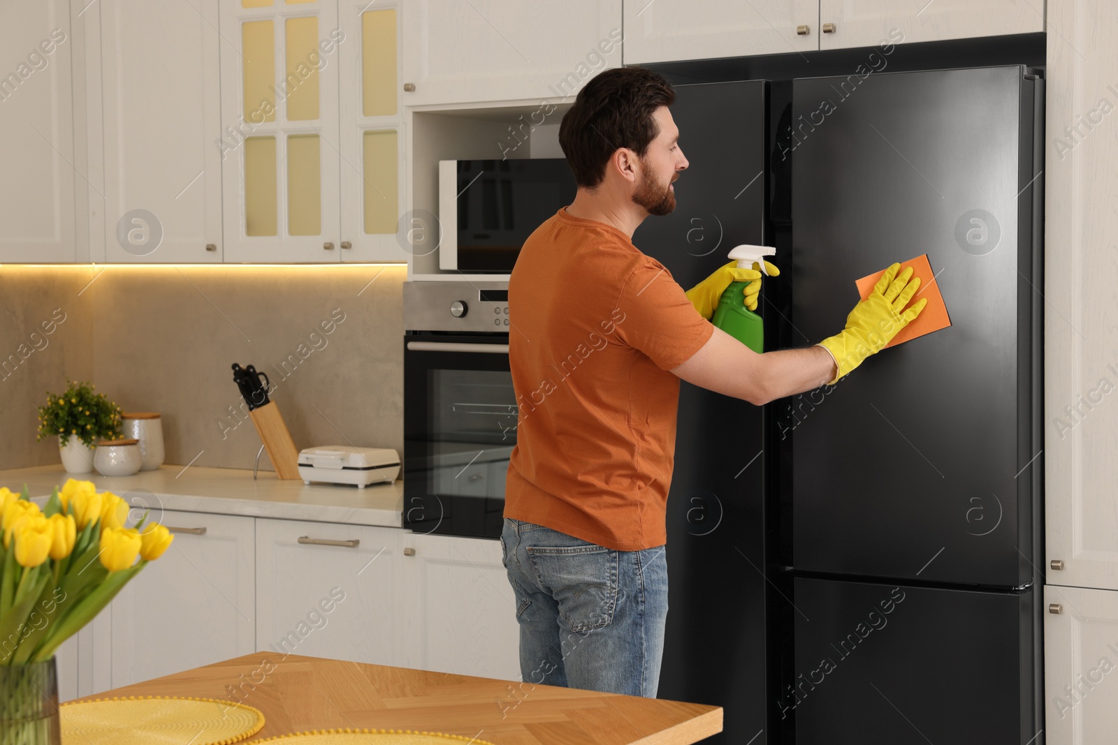 Photo of Spring cleaning. Man tidying up kitchen at home