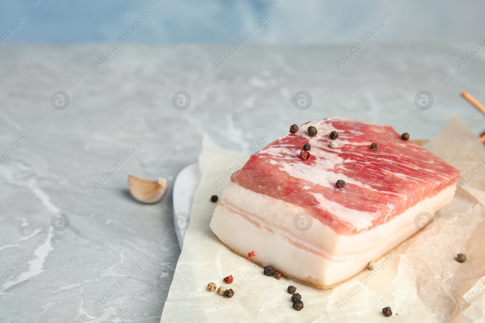 Photo of Pork fatback and pepper on grey stone table. Space for text