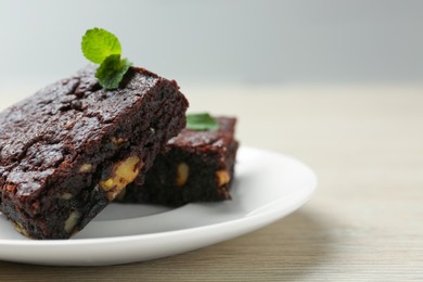 Delicious brownies with nuts and mint on white wooden table, closeup. Space for text