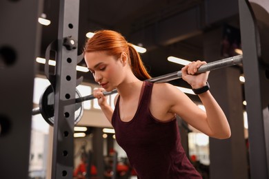 Athletic young woman with barbell training in gym, low angle view