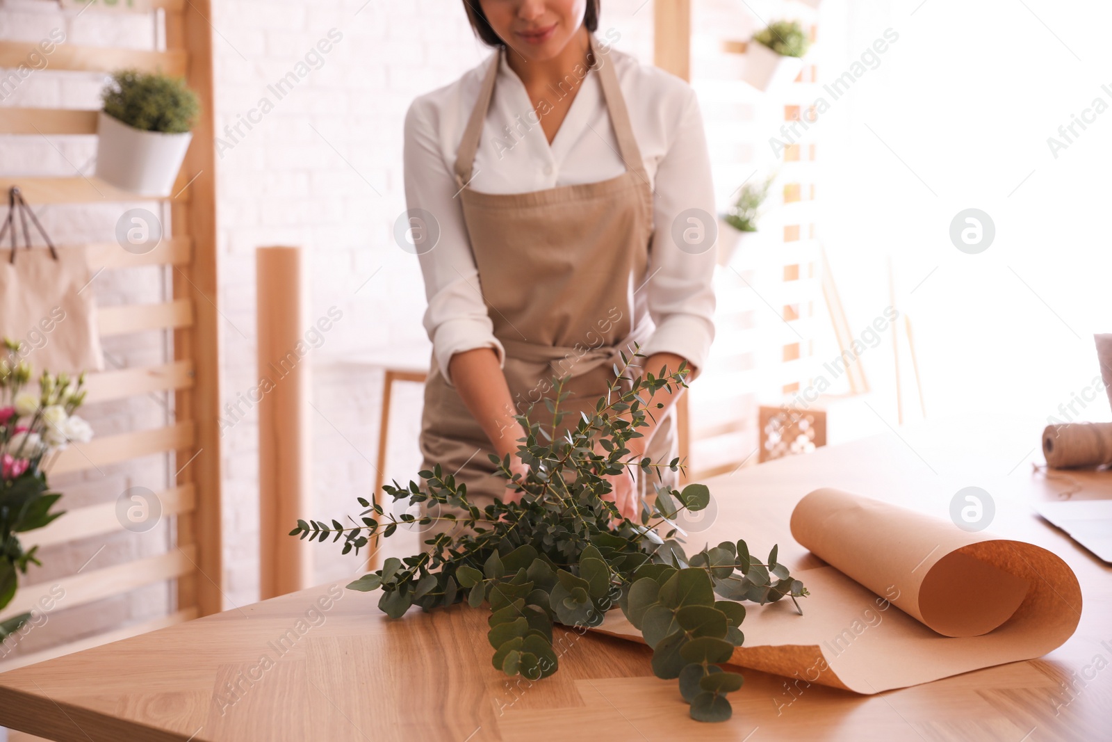 Photo of Florist making beautiful bouquet at table in workshop, closeup