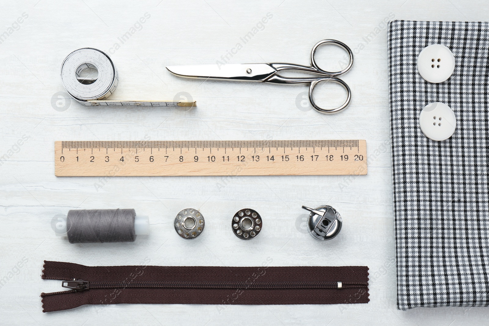 Photo of Flat lay composition with different sewing supplies and fabric on white wooden table