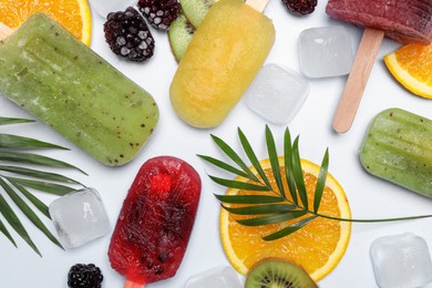 Photo of Delicious popsicles, fresh fruits and ice cubes on light background, flat lay