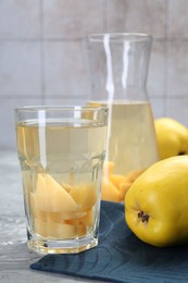 Photo of Delicious quince drink and fresh fruits on grey table