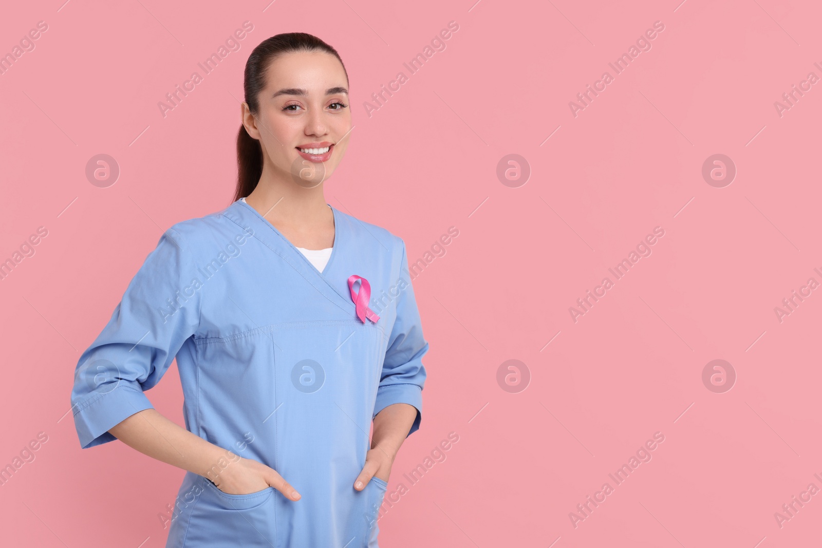 Photo of Mammologist with pink ribbon on color background, space for text. Breast cancer awareness