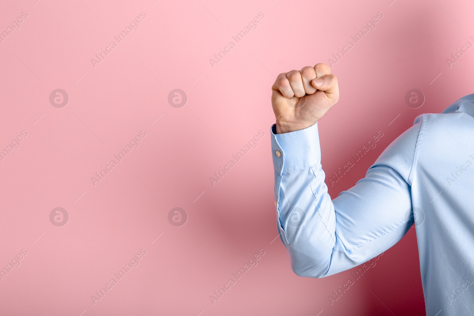 Photo of Young man showing clenched fist on color background. Space for text