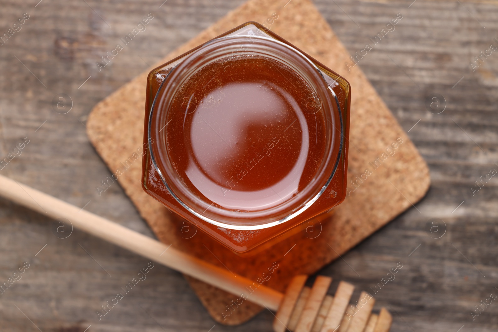 Photo of Sweet honey in jar and dipper on wooden table, flat lay