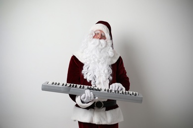 Santa Claus with synthesizer on light background. Christmas music