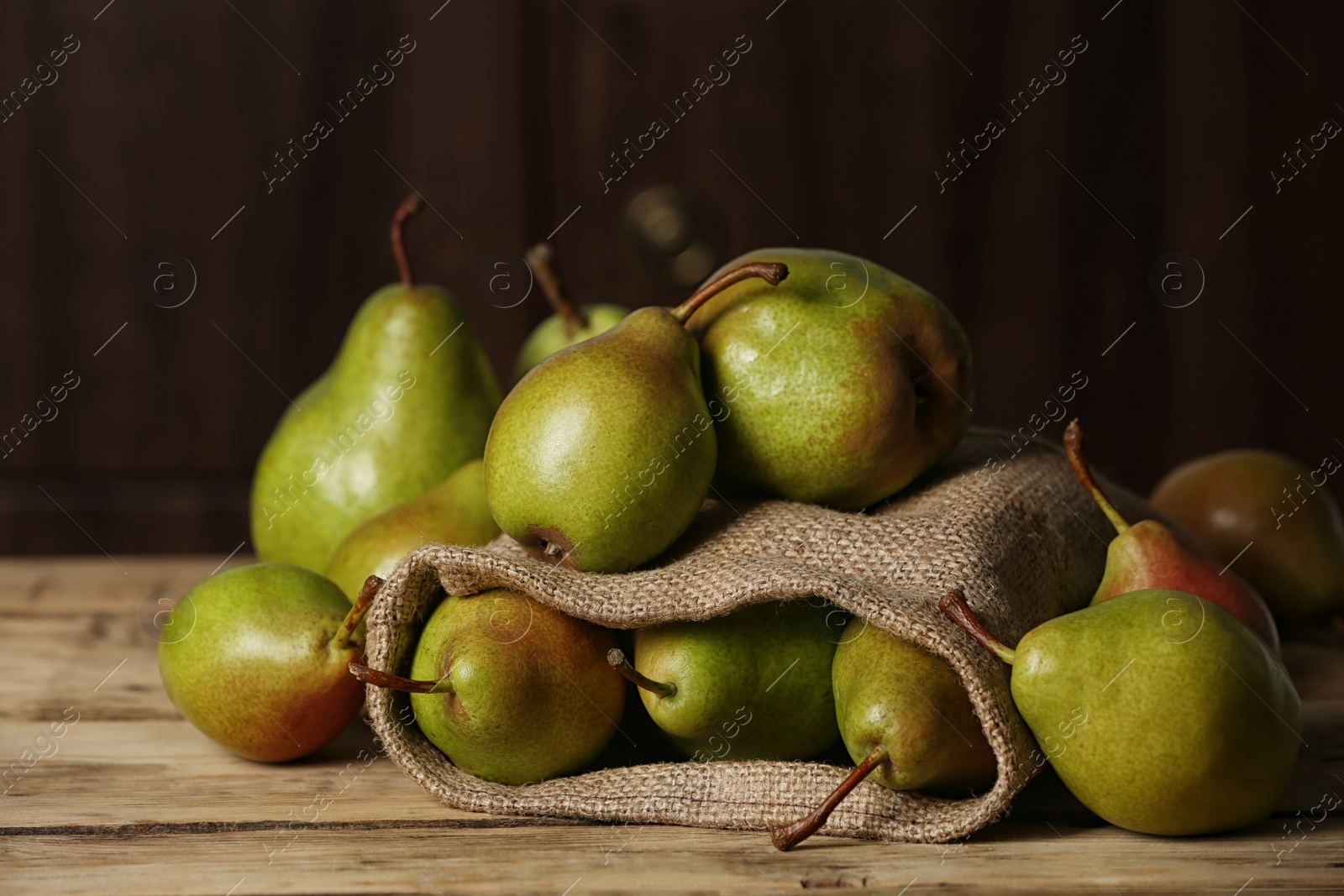 Photo of Fresh ripe pears on wooden table against dark background