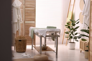 Photo of Comfortable massage table with clean towels in spa center