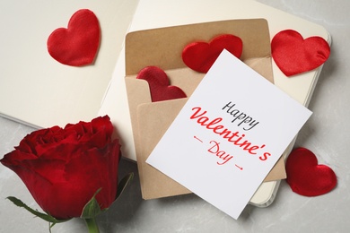 Image of Happy Valentine's Day. Composition with greeting card, rose and notebook on light grey marble table, above view 