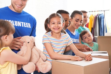 Volunteers with children sorting donation goods indoors