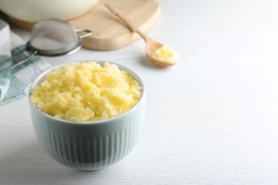 Photo of Bowl of Ghee butter on white wooden table. Space for text