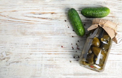 Flat lay composition with jar of pickled cucumbers on white wooden table, space for text