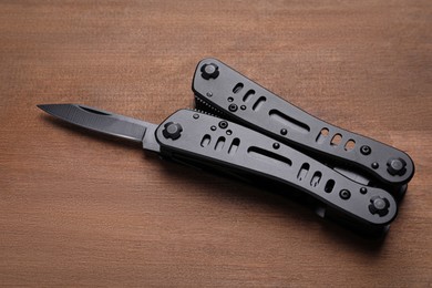 Photo of Modern compact portable multitool on wooden table