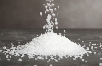 Natural sea salt falling into pile on grey table