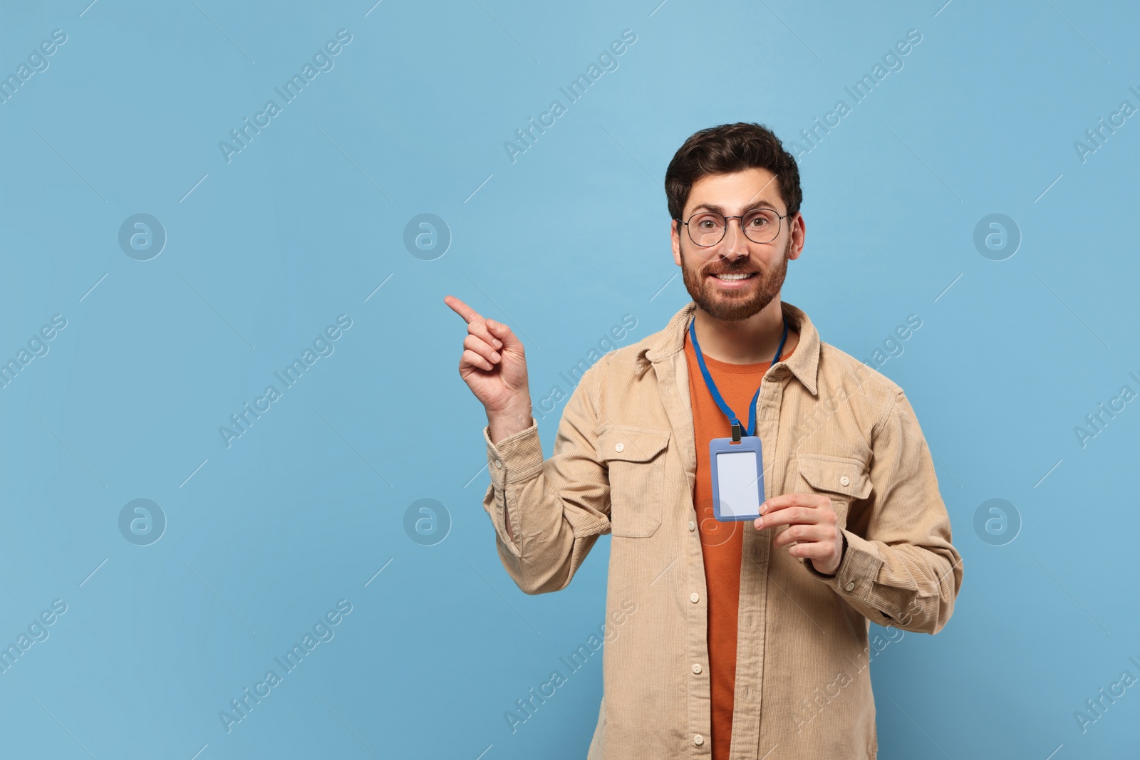 Photo of Smiling man showing VIP pass badge on light blue background, space for text