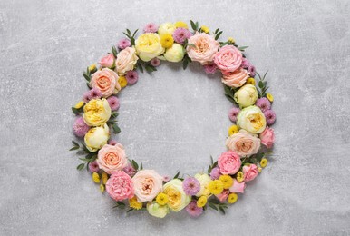 Photo of Wreath made of beautiful flowers and green leaves on light grey background, flat lay. Space for text