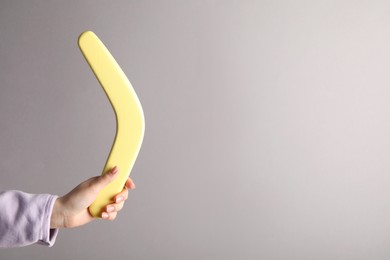 Photo of Woman holding boomerang on grey background, closeup. Space for text