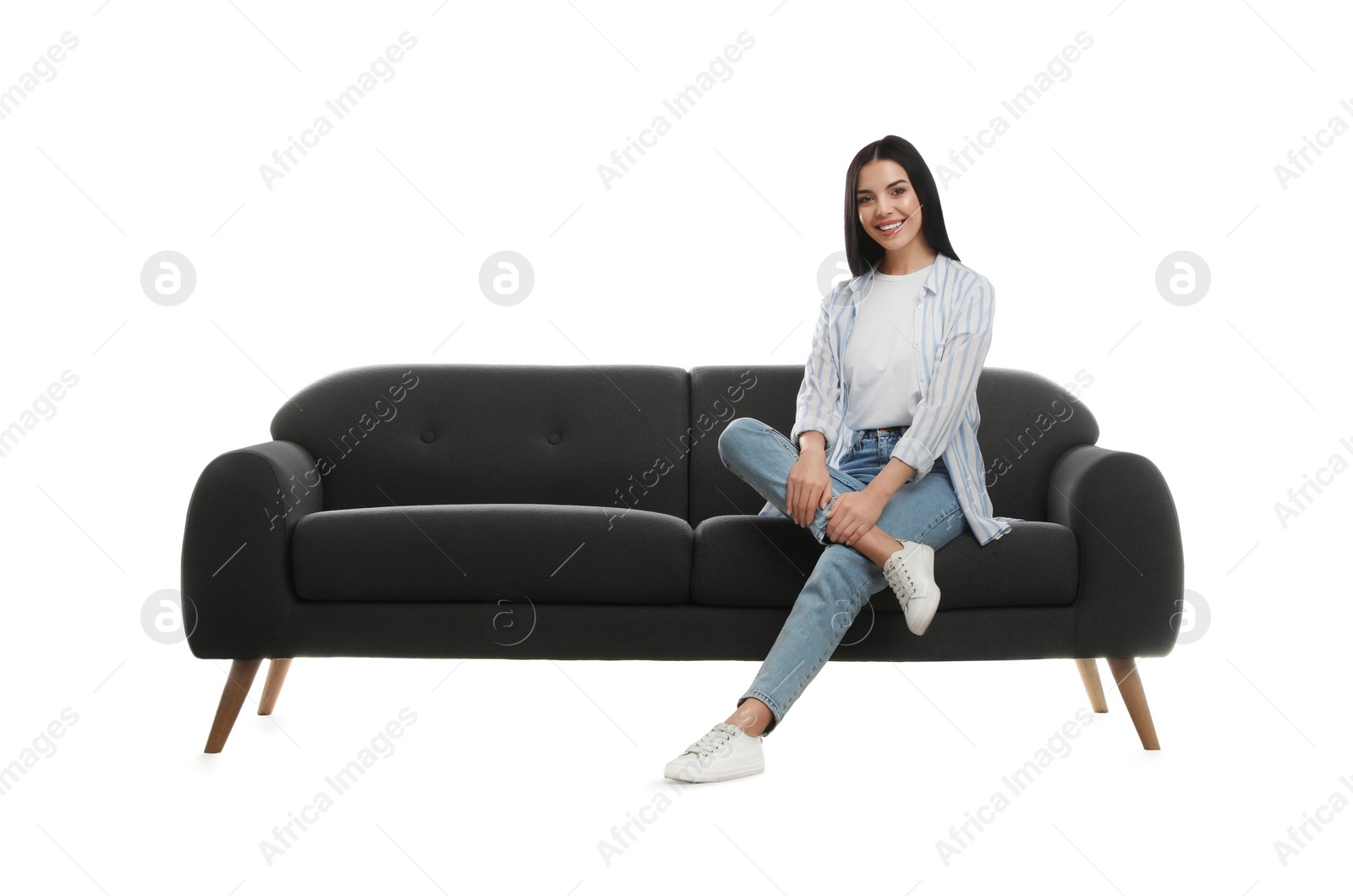 Photo of Young woman relaxing on comfortable grey sofa against white background