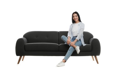 Young woman relaxing on comfortable grey sofa against white background