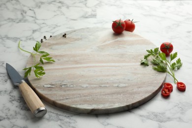 Photo of Cutting board, parsley, pepper and tomatoes on white marble table. Space for text