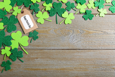 Photo of Flat lay composition with clover leaves on wooden table, space for text. St. Patrick's Day celebration