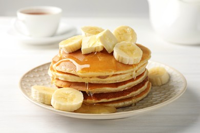 Photo of Delicious pancakes with bananas, honey and butter on white wooden table, closeup