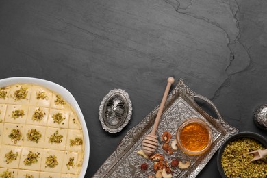 Photo of Making delicious baklava. Raw dough with ingredients on black textured table, flat lay and space for text
