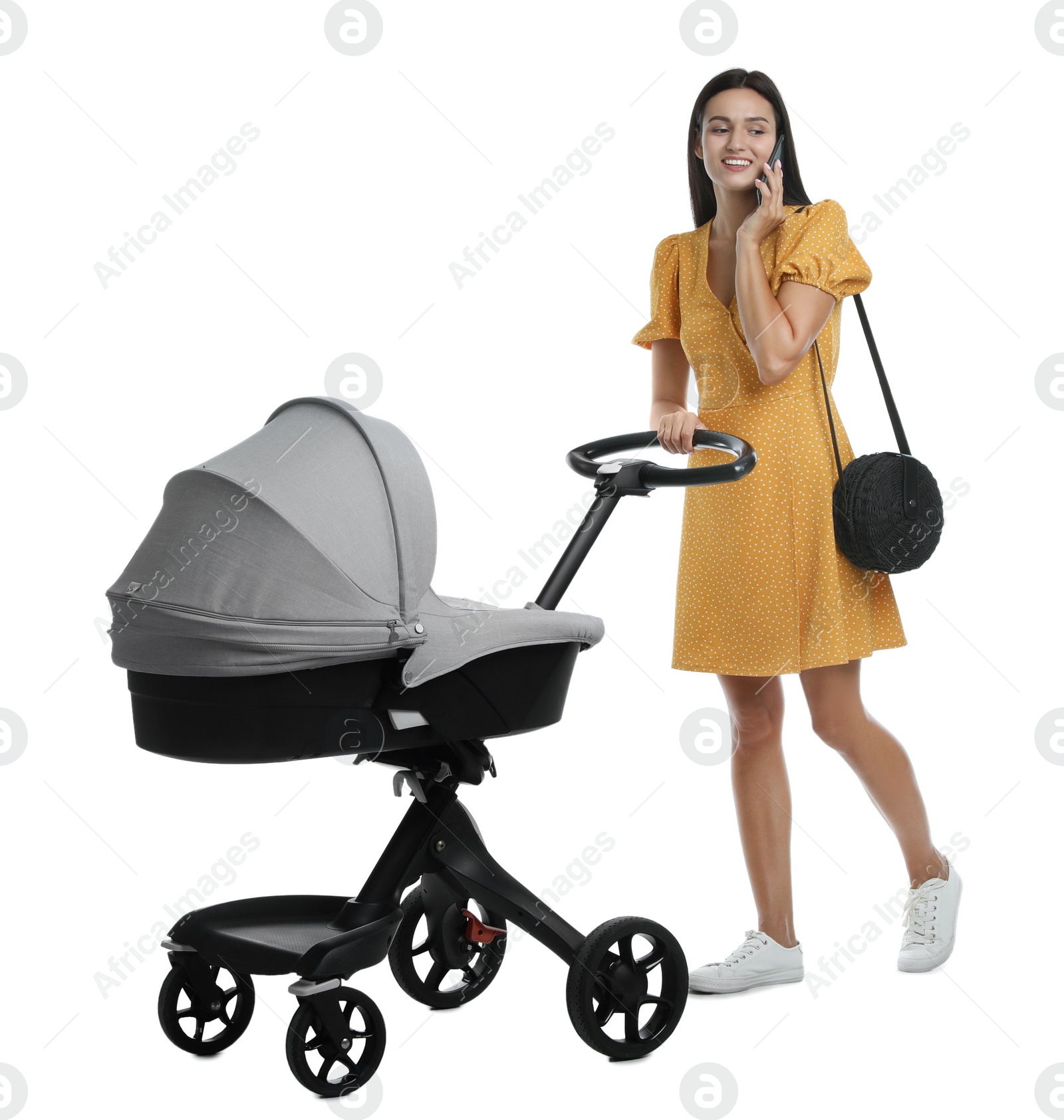 Photo of Happy young woman with baby stroller talking on smartphone against white background