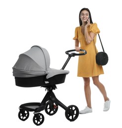 Happy young woman with baby stroller talking on smartphone against white background