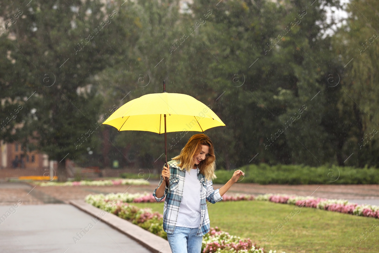 Photo of Happy young woman with umbrella under rain in park