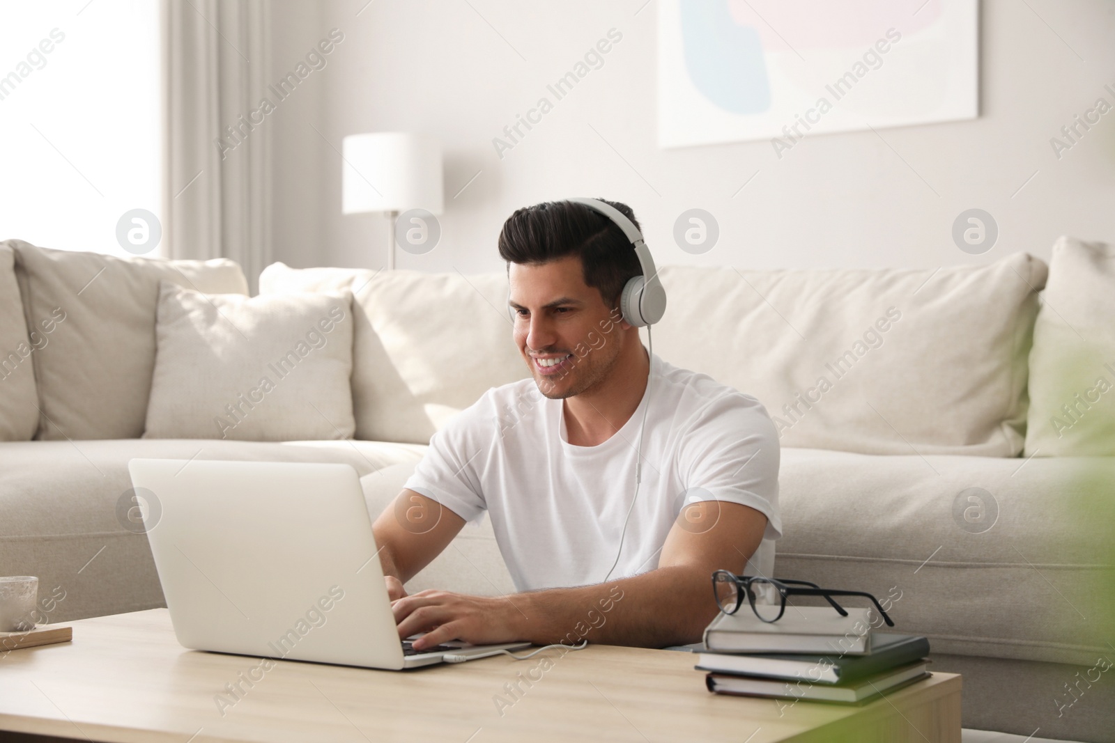 Photo of Man with laptop and headphones at table indoors