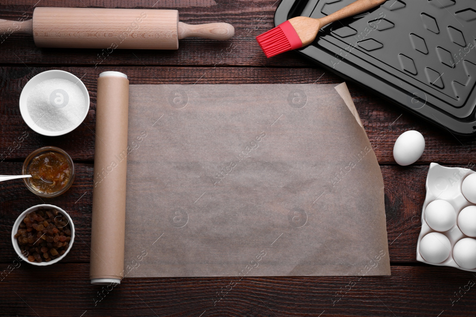 Photo of Roll of baking parchment paper and ingredients on wooden table, flat lay