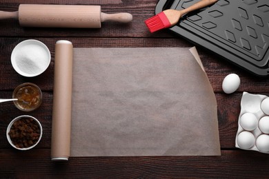 Photo of Roll of baking parchment paper and ingredients on wooden table, flat lay