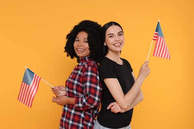 4th of July - Independence Day of USA. Happy women with American flags on yellow background