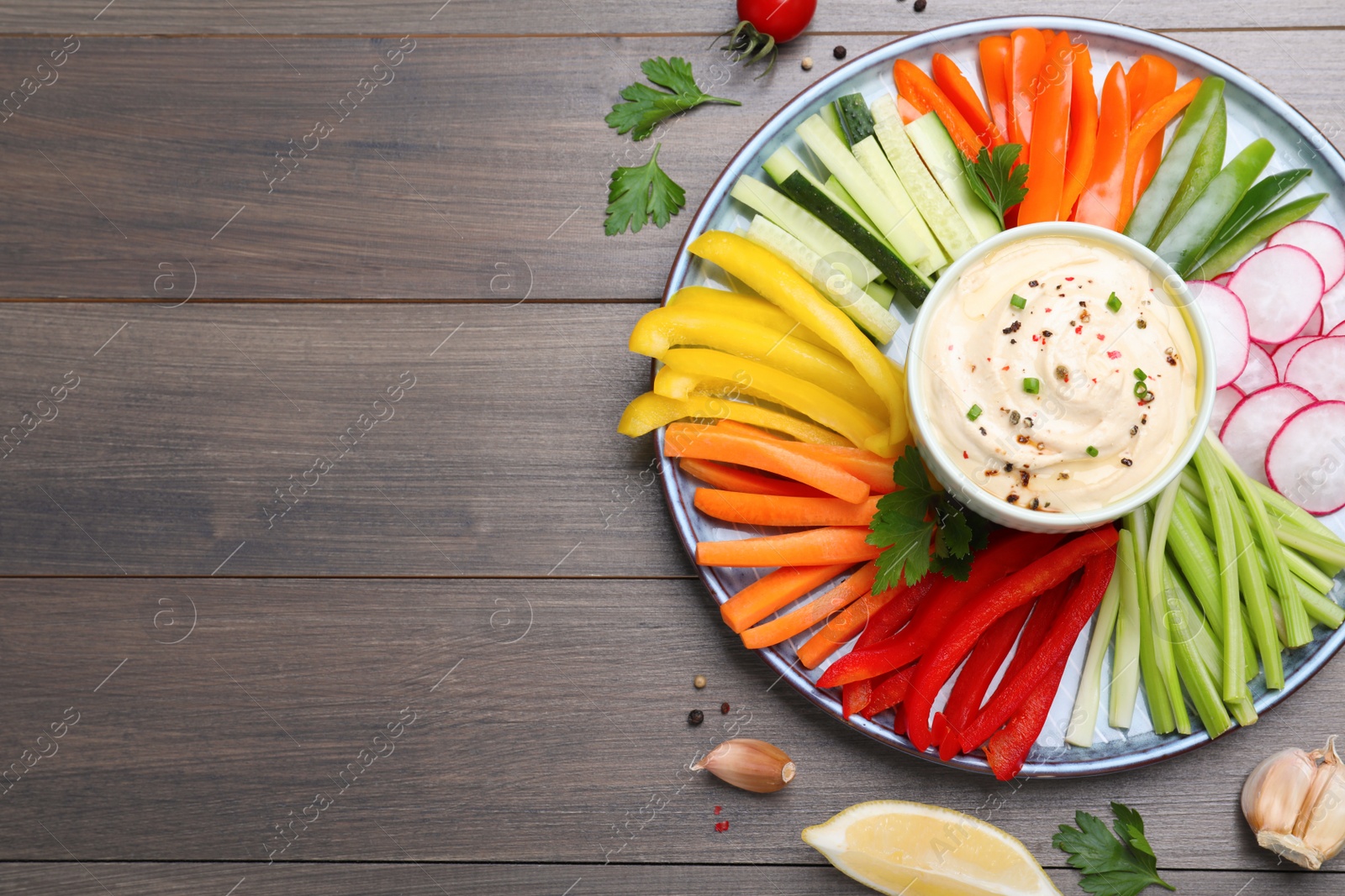 Photo of Fresh raw vegetable sticks and sauce on grey wooden table, flat lay. Space for text