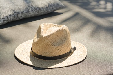 Stylish straw hat and pillow on grey fabric outdoors